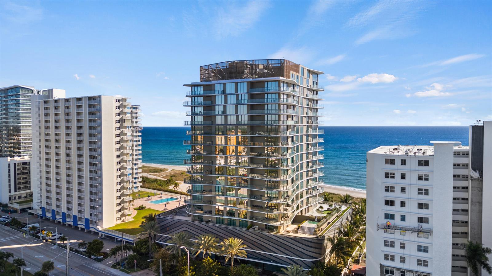 An aerial view shows a modern glass-balcony high-rise building situated between two older residential towers — 730 N Ocean Boulevard # 1402, Pompano Beach FL 33062, POMPANO BEACH, FL