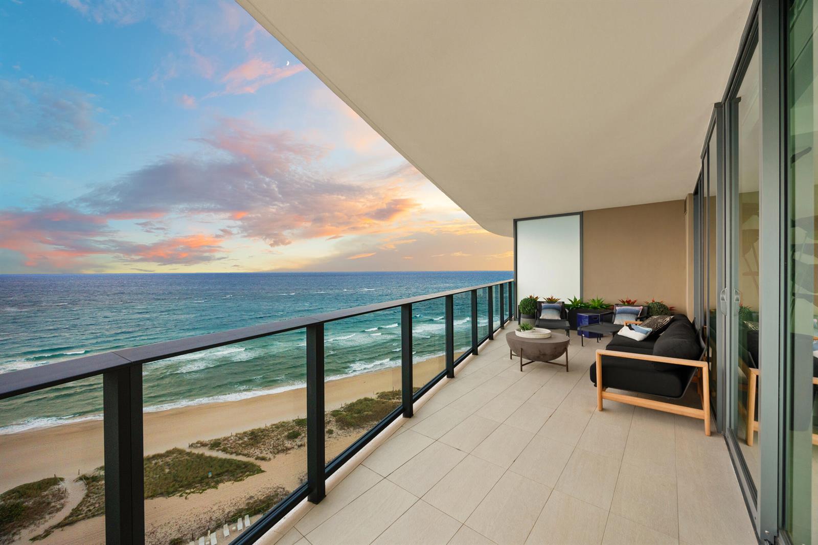 A modern balcony with outdoor furniture overlooks a sandy beach and the ocean at sunset — 730 N Ocean Boulevard # 1402, Pompano Beach FL 33062, POMPANO BEACH, FL