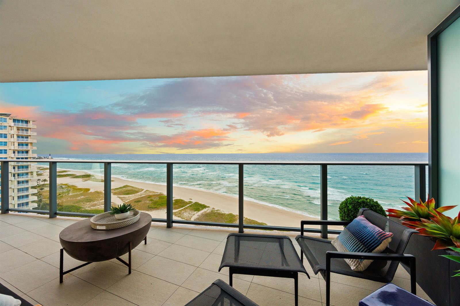 A balcony with outdoor furniture overlooks a sandy beach and the ocean at sunset — 730 N Ocean Boulevard # 1402, Pompano Beach FL 33062, POMPANO BEACH, FL