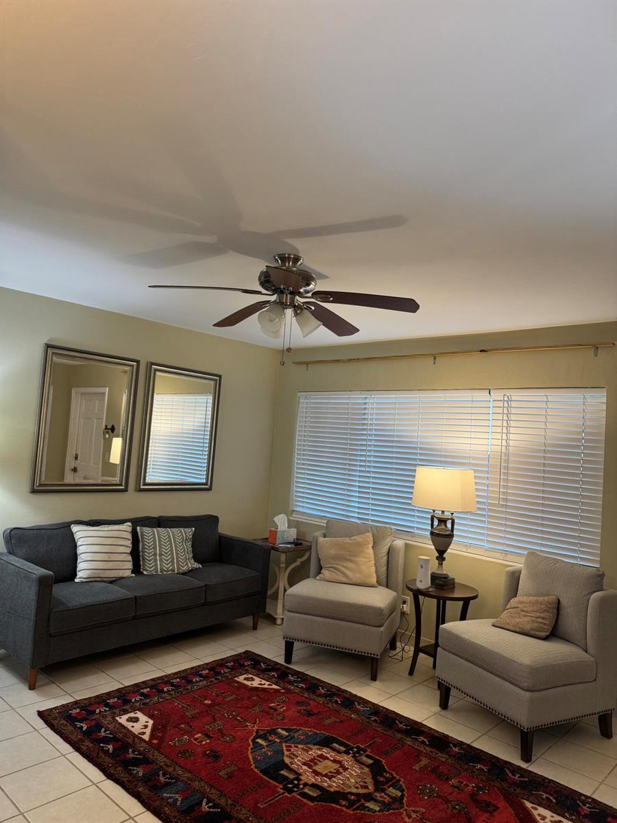 A living room features a dark sofa, two light armchairs, a patterned rug, and blinds — 3362 Cynthia Lane # 107, FL 33461, FL