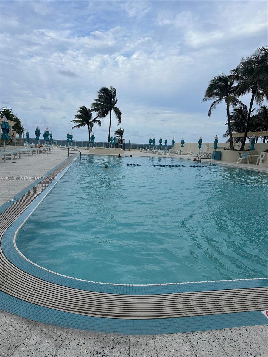 An outdoor swimming pool is surrounded by a deck with lounge chairs and palm trees — 2501 S Ocean Dr # 1530, Hollywood FL 33019, HOLLYWOOD, FL
