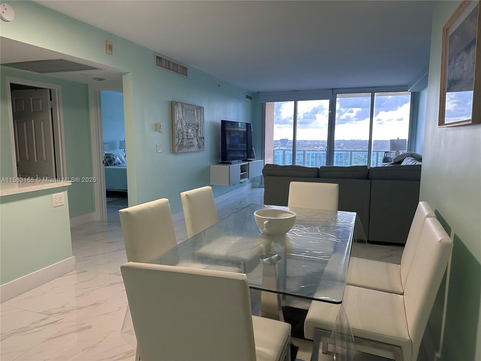 A dining area with a glass table and white chairs sits before a living room — 2501 S Ocean Dr # 1530, Hollywood FL 33019, HOLLYWOOD, FL
