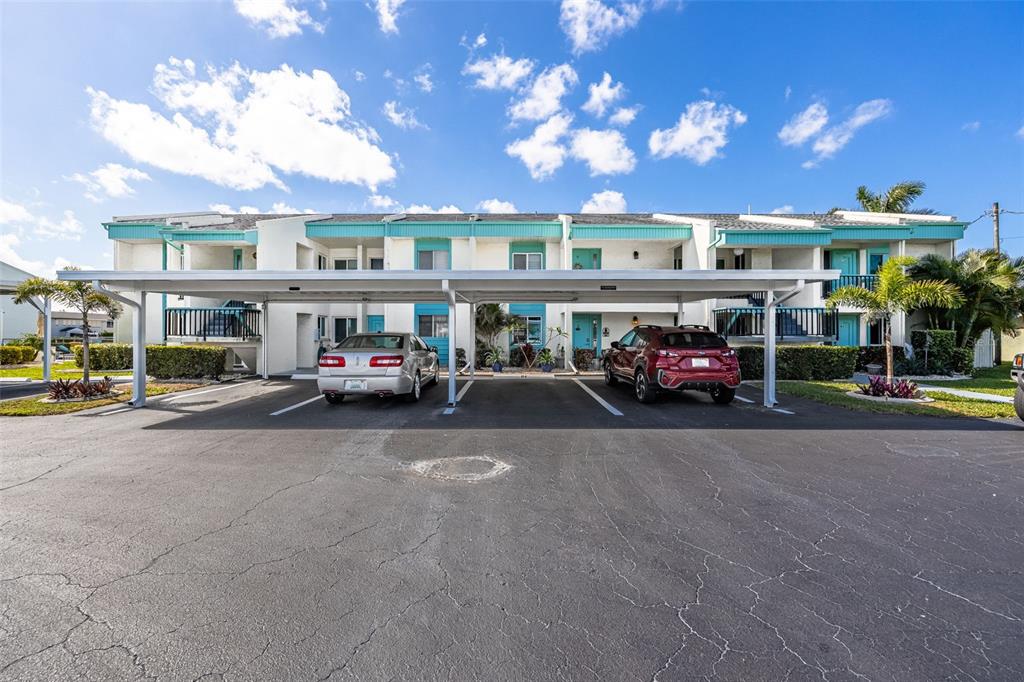 A two-story apartment building features a covered parking area with two cars parked underneath — 1322 SE 40TH STREET UNIT 2, CAPE CORAL, FL