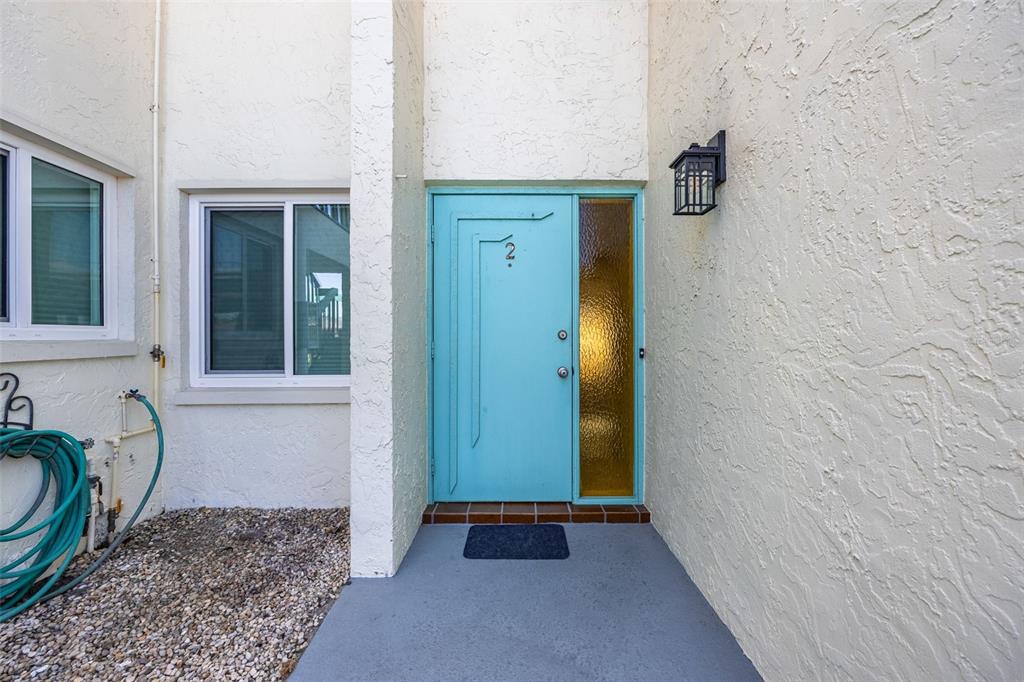 A teal front door with a side window and a hose on the gravel ground — 1322 SE 40TH STREET UNIT 2, CAPE CORAL, FL
