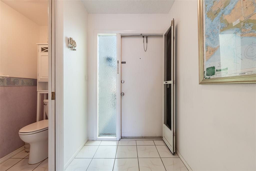 A tiled entryway features a white front door with a sidelight and an adjacent bathroom — 1322 SE 40TH STREET UNIT 2, CAPE CORAL, FL