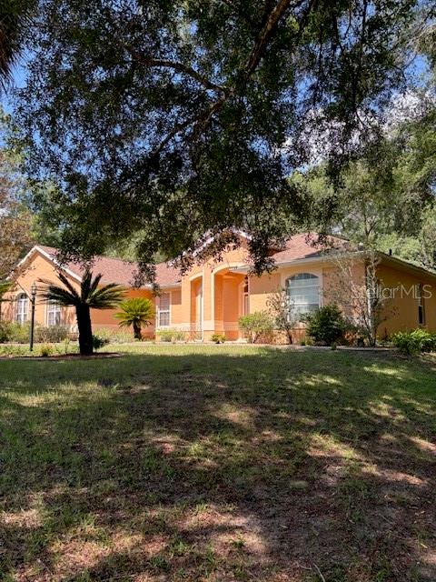 A single-story peach-colored house with a shingled roof sits on a grassy lot with trees — 9273 SW 197TH CIR, DUNNELLON, FL