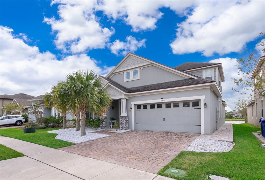A two-story gray house with a stone-accented entrance, palm trees, and a paved driveway — 3026 JARDIN STREET, KISSIMMEE, FL