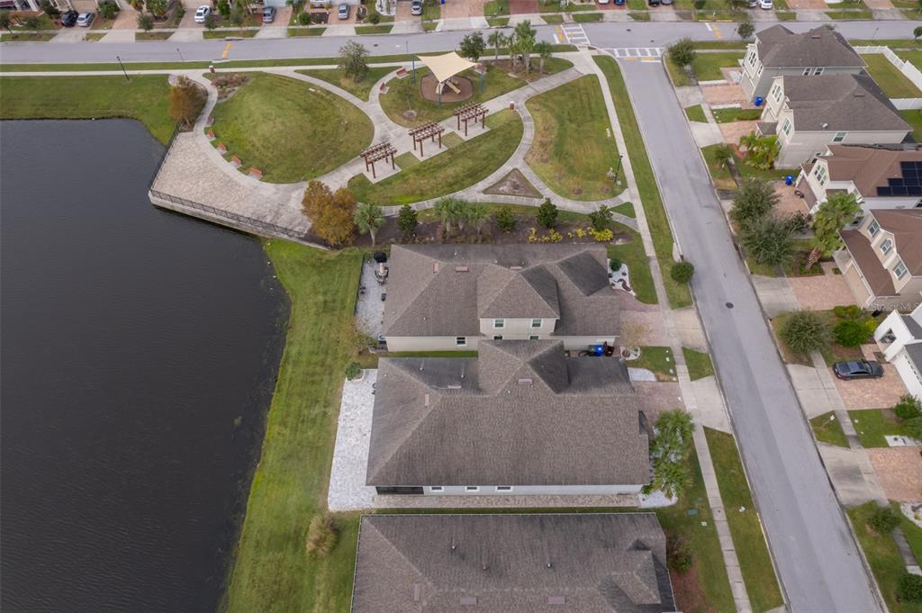 An aerial view shows three houses situated next to a lake and a public park — 3026 JARDIN STREET, KISSIMMEE, FL