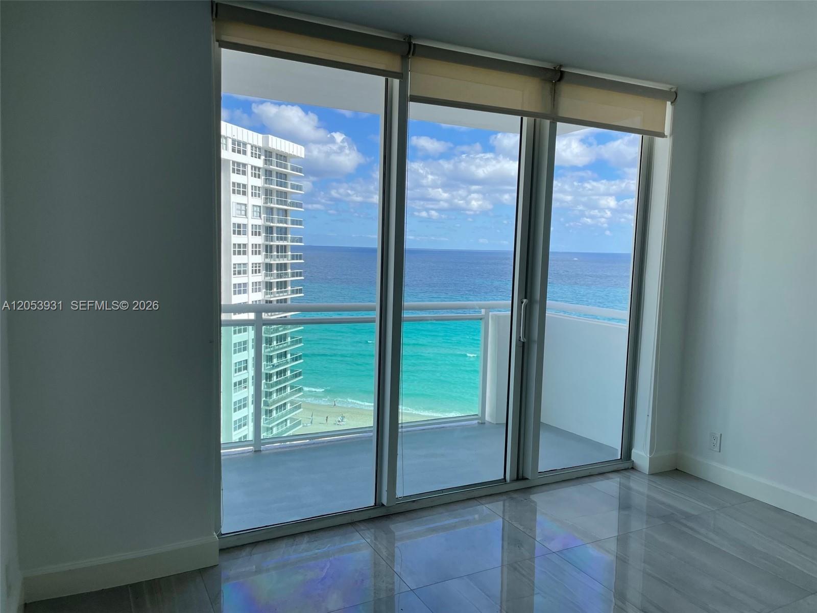 A room with gray tile flooring features a large glass sliding door overlooking the ocean — 3001 S Ocean Dr # 1449, Hollywood FL 33019, HOLLYWOOD, FL