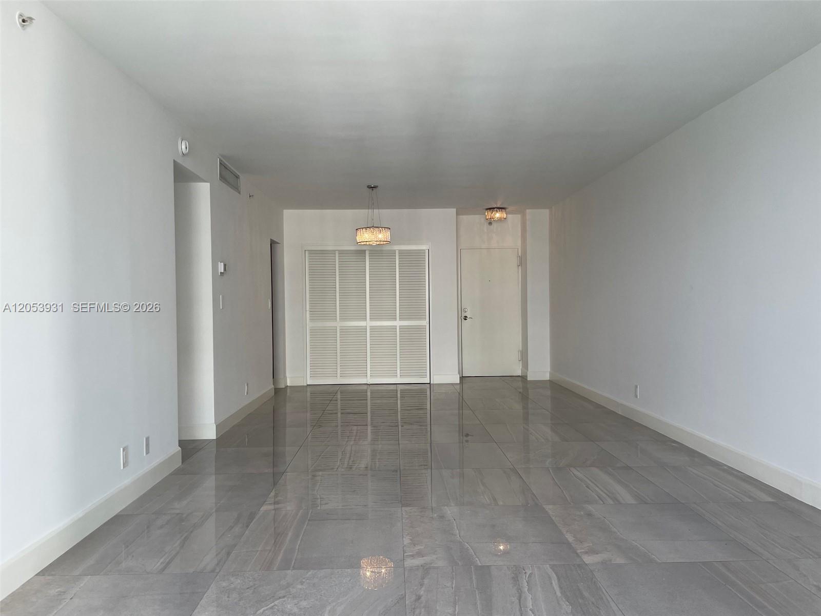 A minimalist room features large gray tile flooring, white walls, and a louvered closet door — 3001 S Ocean Dr # 1449, Hollywood FL 33019, HOLLYWOOD, FL