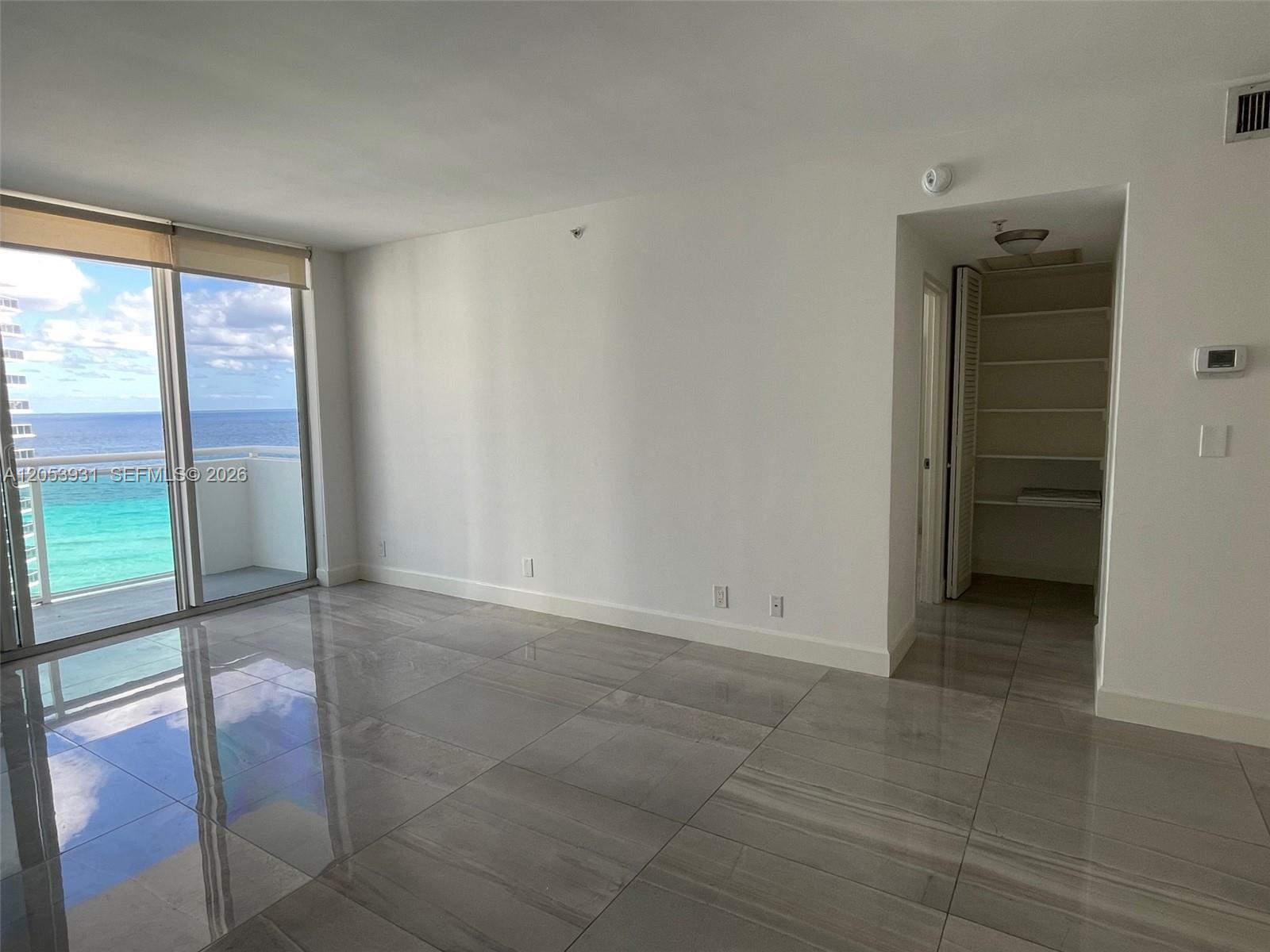 An empty room with large gray floor tiles, white walls, and a sliding glass balcony door — 3001 S Ocean Dr # 1449, Hollywood FL 33019, HOLLYWOOD, FL