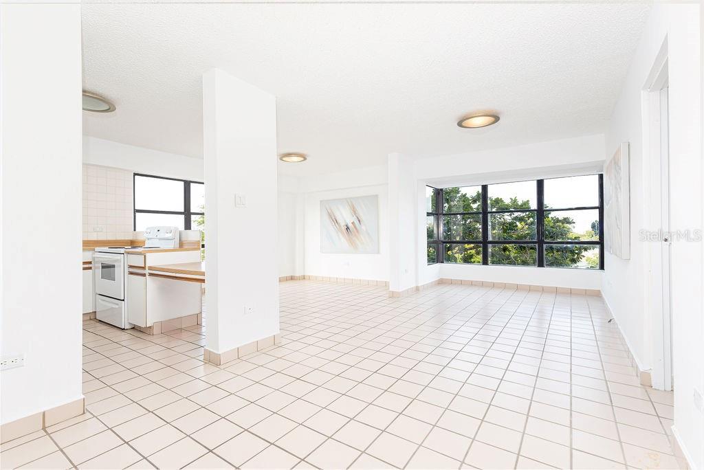 A bright, open-concept living and kitchen area features white tile flooring and large windows — 277 SAN JORGE UNIT 202, SAN JUAN, PR