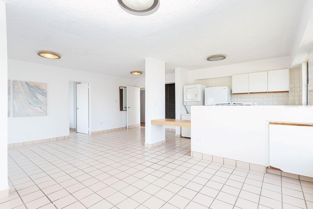 An open-concept room with white tile flooring, white walls, and a kitchen with white cabinetry — 277 SAN JORGE UNIT 202, SAN JUAN, PR