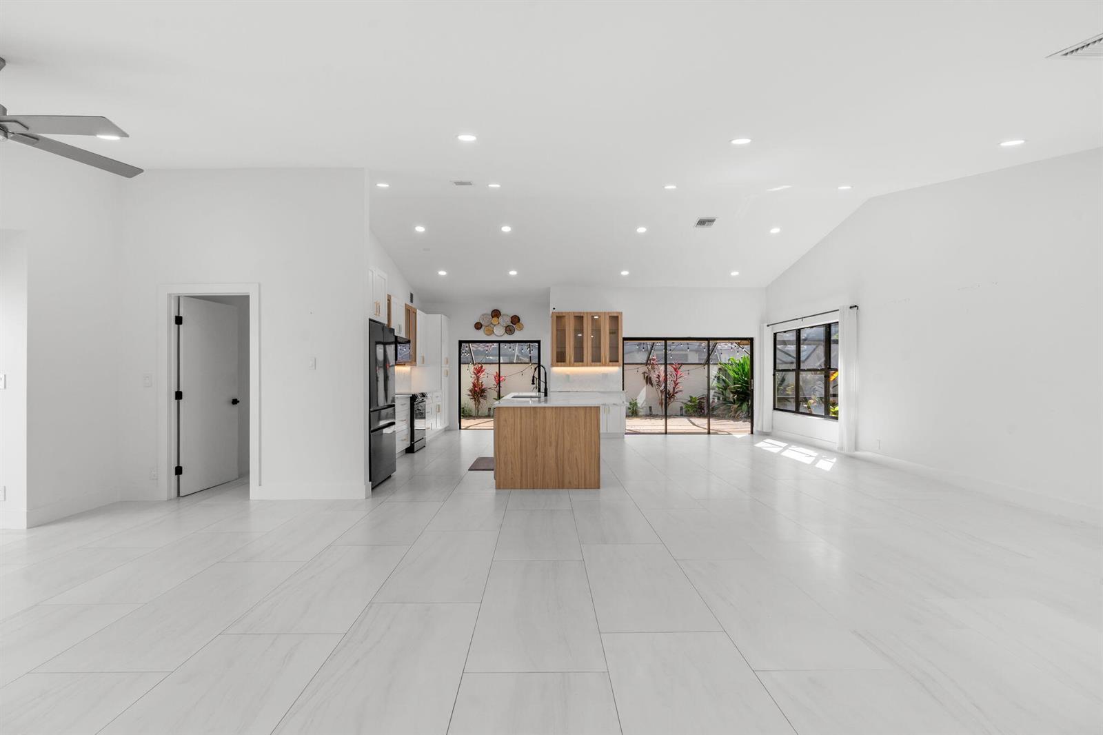A bright, open-concept kitchen and living area features white walls, light tile flooring, and cabinetry — 21326 Campo Allegro Drive, Boca Raton FL 33433, BOCA RATON, FL