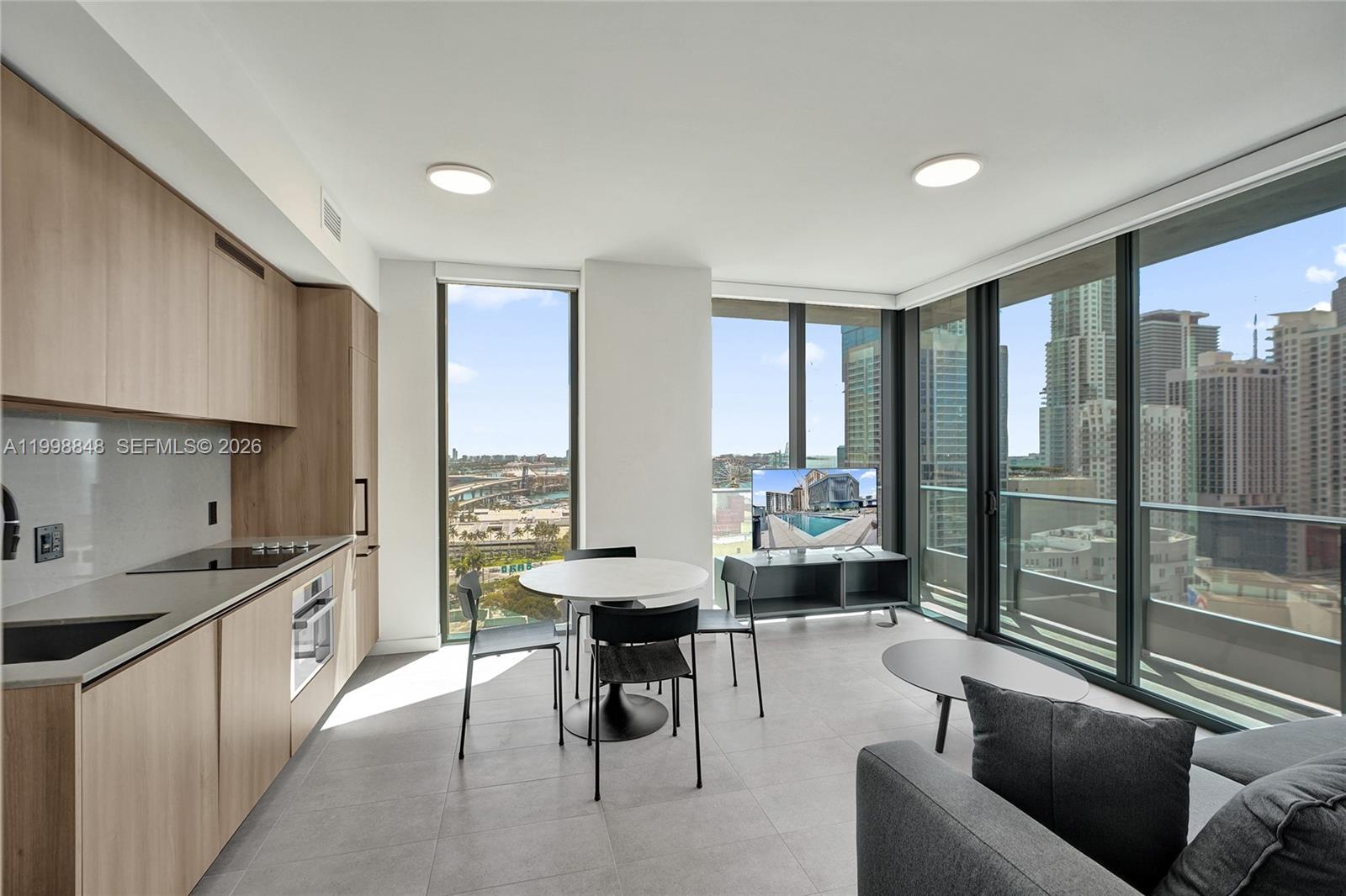 A modern apartment living area features a kitchen, dining set, and floor-to-ceiling windows — 121 NE 5th ST # 2101, Miami FL 33132, MIAMI, FL