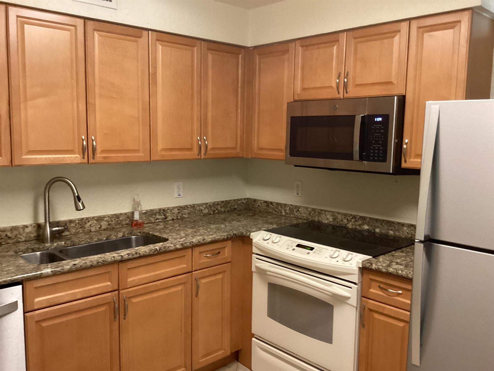 A kitchen features light wood cabinets, granite countertops, a stainless steel microwave, and white appliances — 1000 Spanish River Road # 3k, Boca Raton FL 33432, BOCA RATON, FL