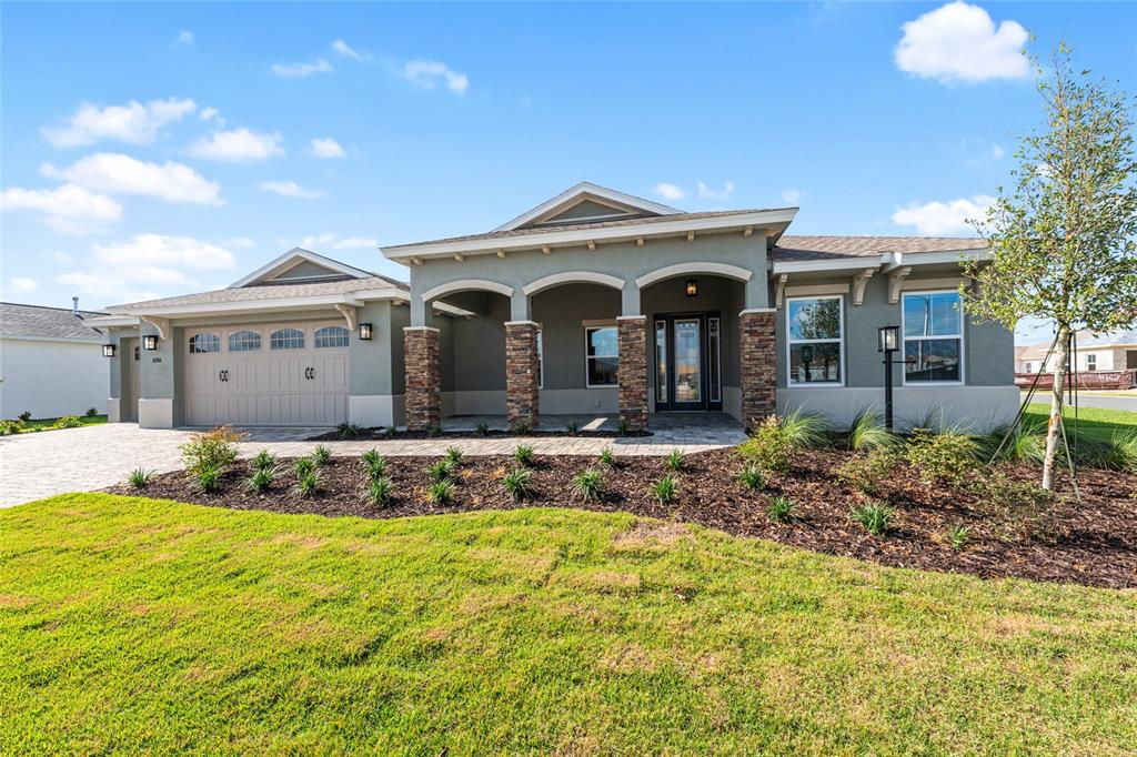 A single-story house with a stone-accented porch, gray stucco exterior, and a two-car garage — 10306 SW 85TH PLACE ROAD, OCALA, FL