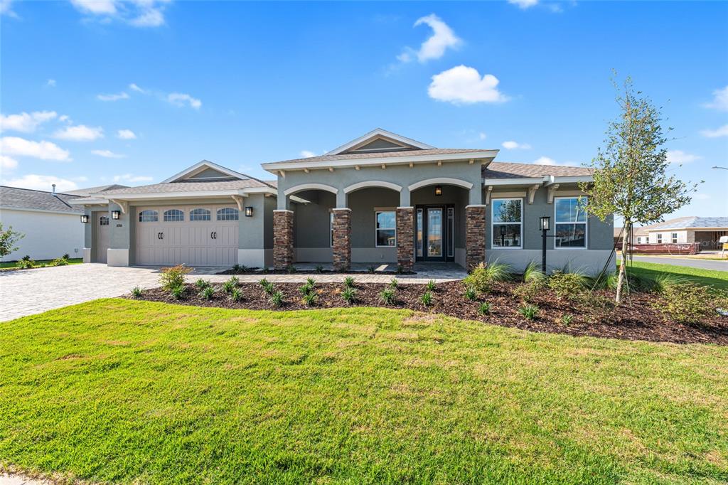 A single-story house with a stone-accented porch, a two-car garage, and a landscaped front yard — 10306 SW 85TH PLACE ROAD, OCALA, FL