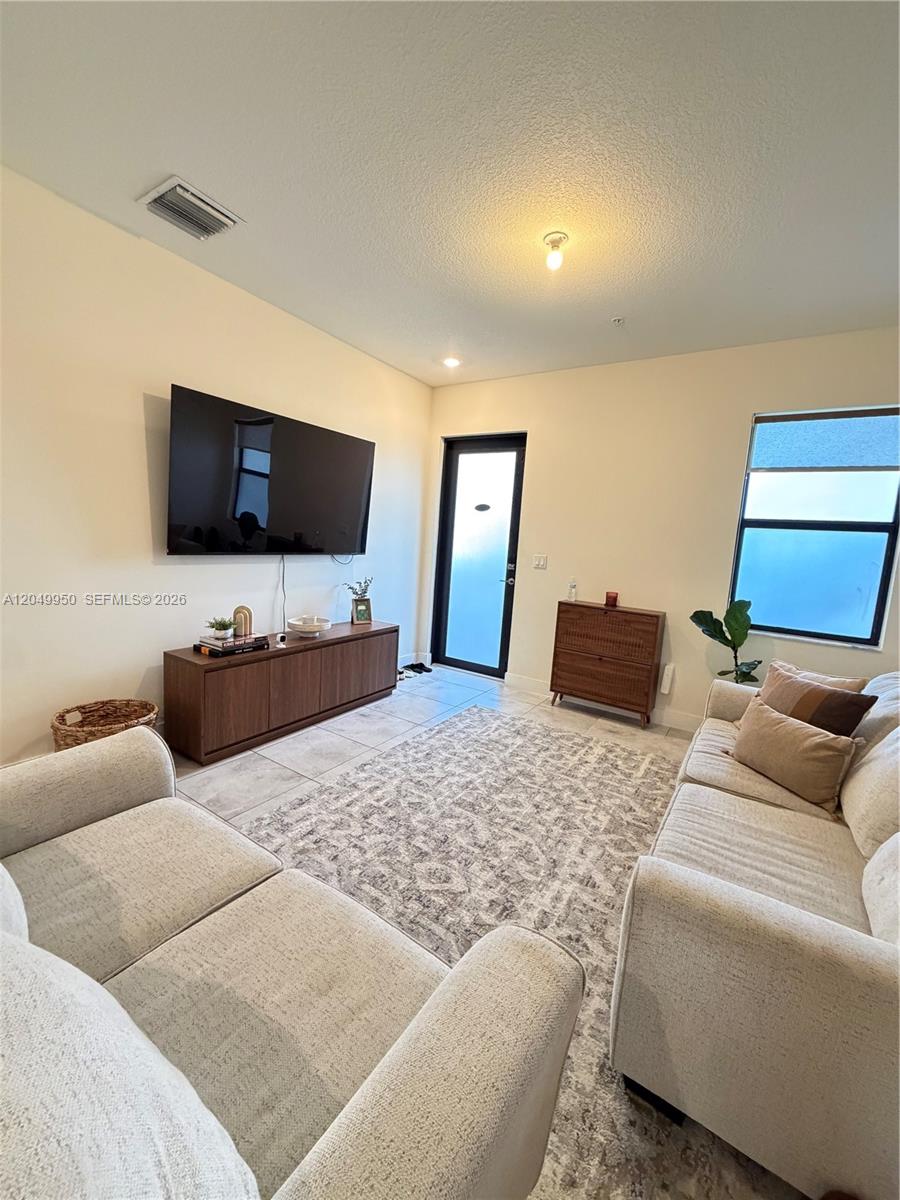 A living room features a wall-mounted television, a media console, two sofas, and tile flooring — 8195 NW 104th Ave # 22, Doral FL 33178, DORAL, FL