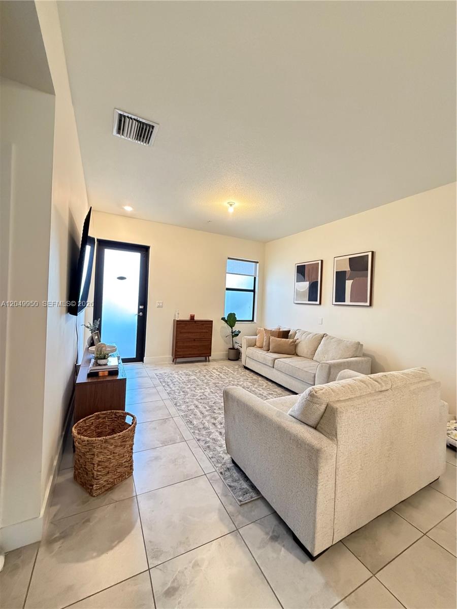 A living room features light tile floors, a neutral sofa, and a wall-mounted television — 8195 NW 104th Ave # 22, Doral FL 33178, DORAL, FL