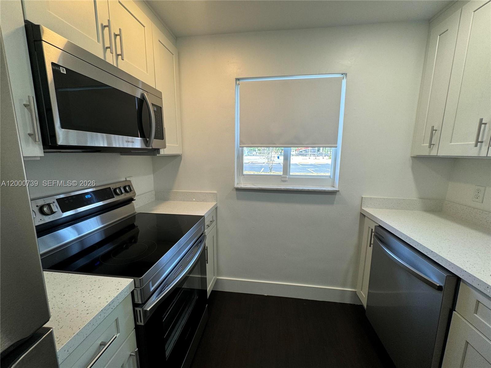 A galley kitchen features white cabinets, stainless steel appliances, and light-colored speckled countertops — 4850 SW 26th Ave # 6, Dania Beach FL 33312, DANIA BEACH, FL