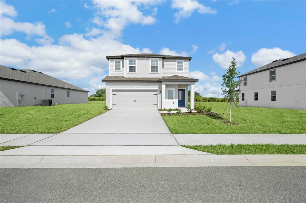 A two-story suburban house with a light gray exterior, a two-car garage, and a driveway — 636 TANGELO TERRACE, BABSON PARK, FL