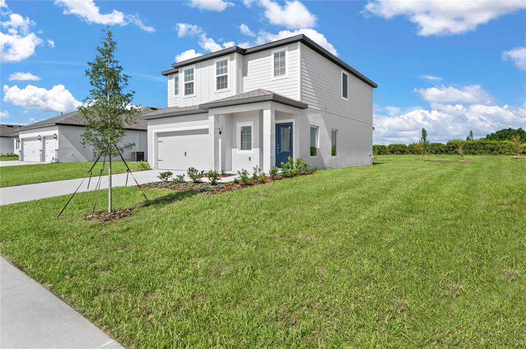 A two-story, light-gray suburban house with a white garage and a blue front door — 636 TANGELO TERRACE, BABSON PARK, FL