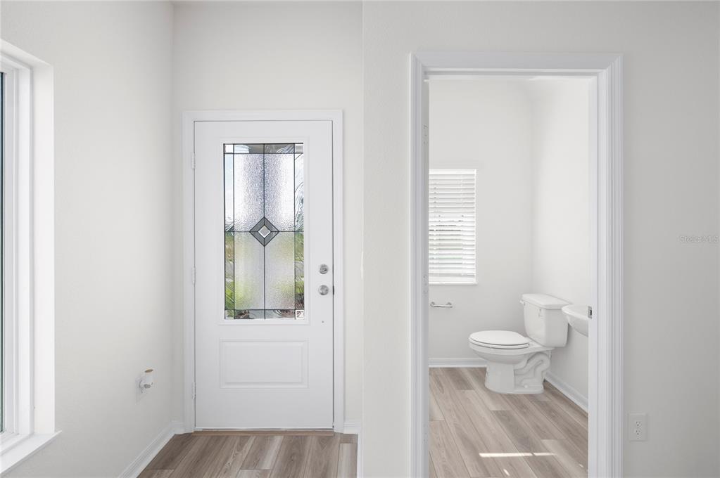 A white front door sits next to an open doorway leading into a small bathroom — 636 TANGELO TERRACE, BABSON PARK, FL