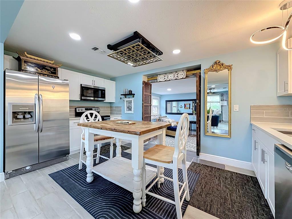 A kitchen features a wooden dining table, stainless steel appliances, and light blue walls — 4831 FAIRFIELD AVENUE S, ST PETERSBURG, FL