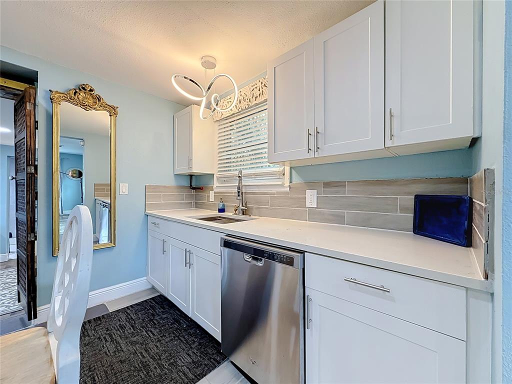 A kitchen features white cabinets, a stainless steel dishwasher, a light blue wall, and a mirror — 4831 FAIRFIELD AVENUE S, ST PETERSBURG, FL