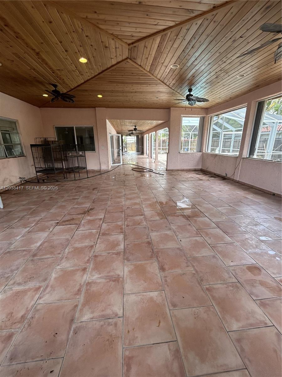 A spacious, covered outdoor patio features a wood-paneled ceiling, tile flooring, and large windows — 8385 SW 105th St, Miami FL 33156, MIAMI, FL