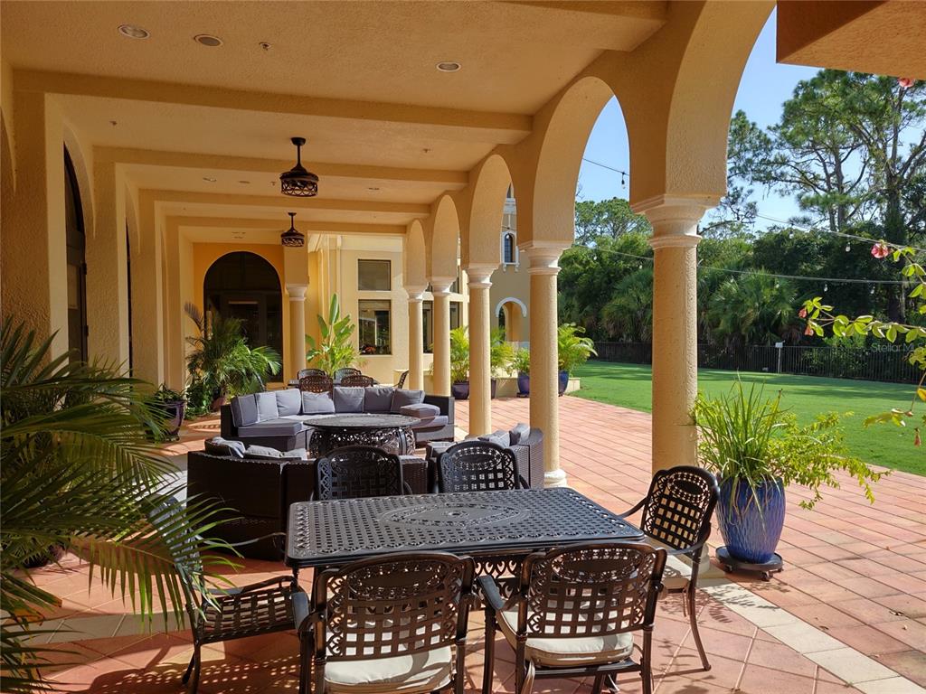 A covered outdoor patio features arched columns, tile flooring, and various seating areas — 150 PADOVA WAY UNIT 43, NOKOMIS, FL