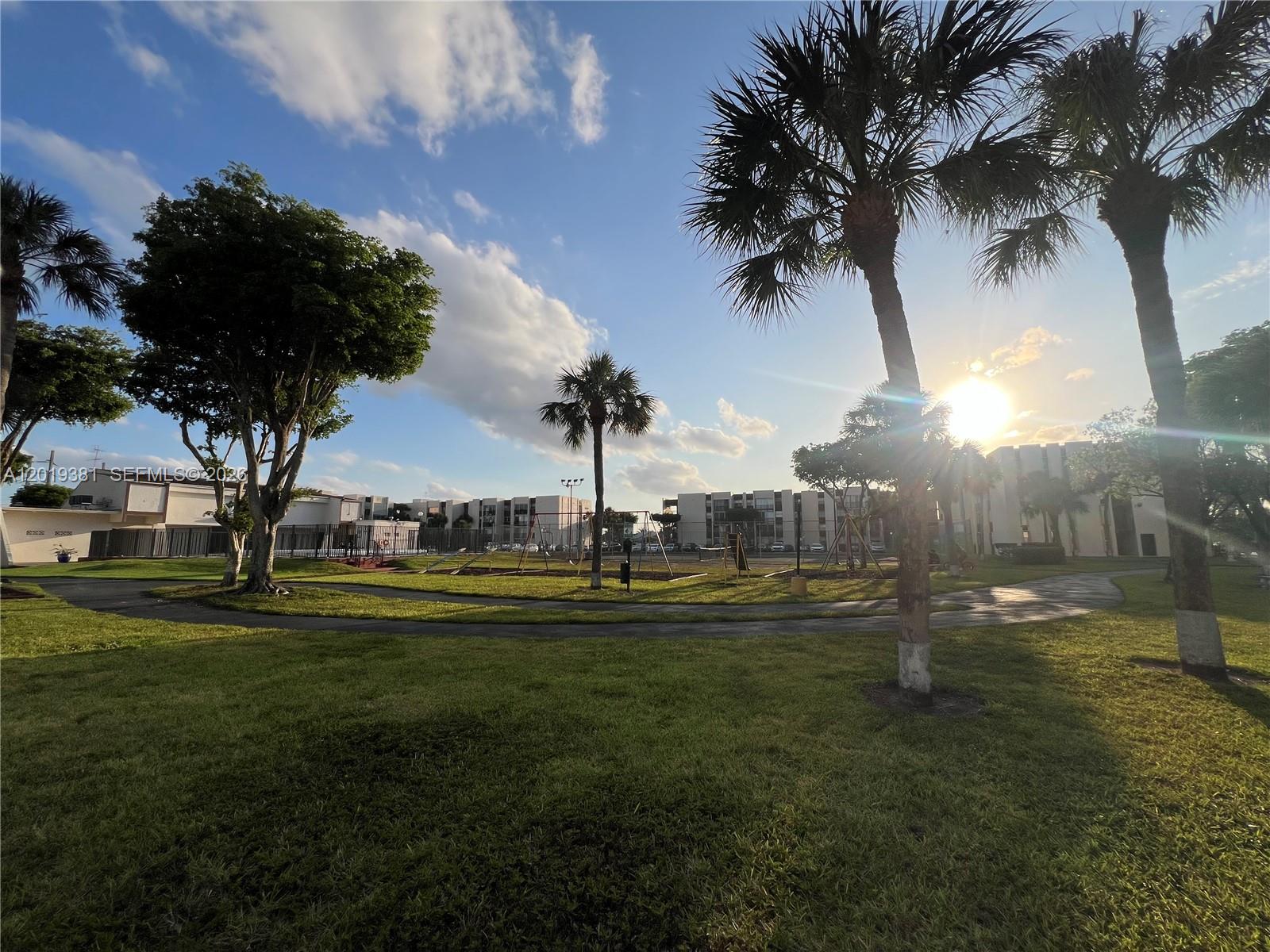 A grassy park area features palm trees, a playground, and apartment buildings under a sunny sky — 9431 SW 4th St # 207, Miami FL 33174, MIAMI, FL