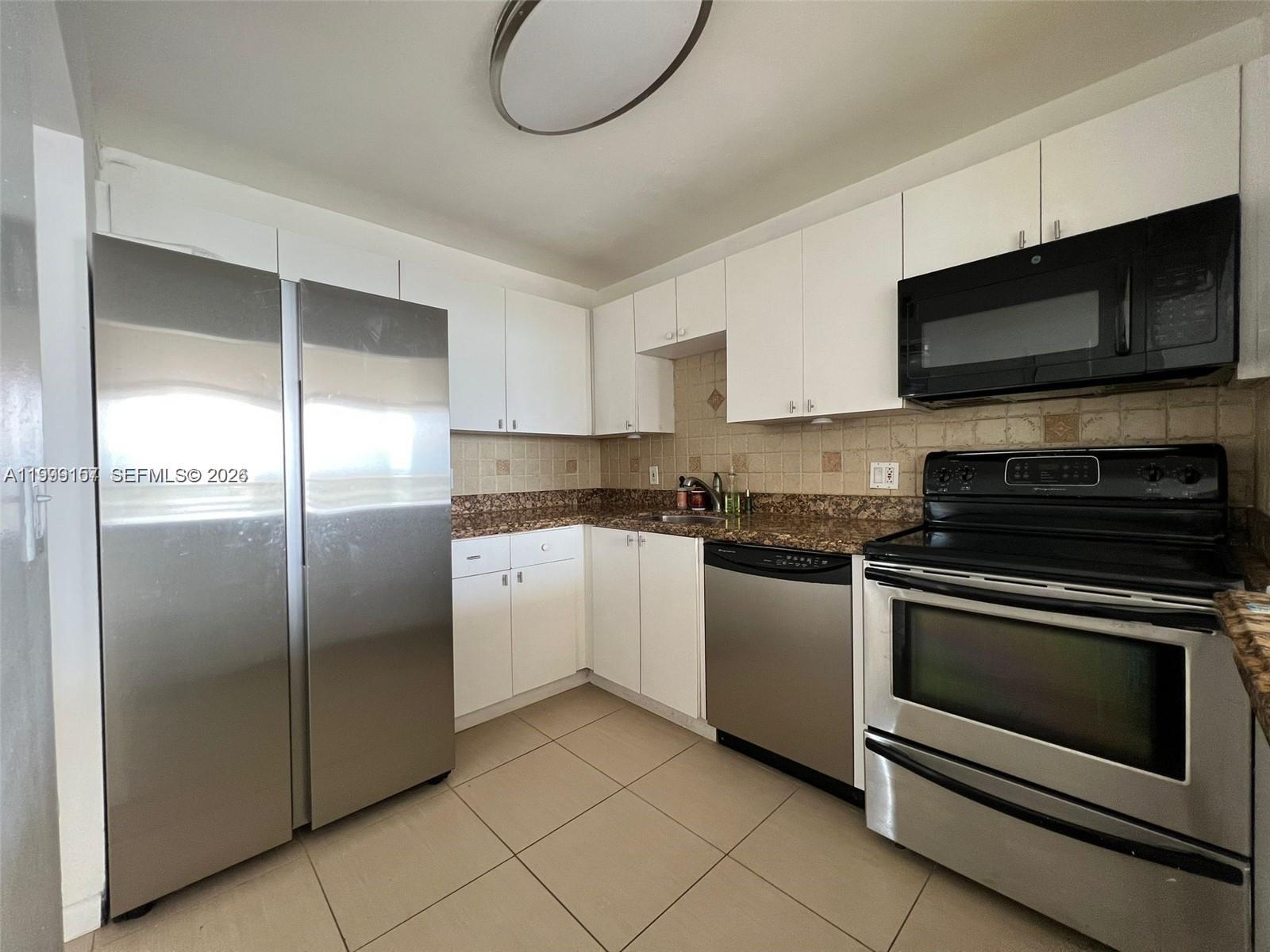 A kitchen features white cabinets, stainless steel appliances, and brown granite countertops — 13499 Biscayne Blvd # 1402, North Miami FL 33181, NORTH MIAMI, FL