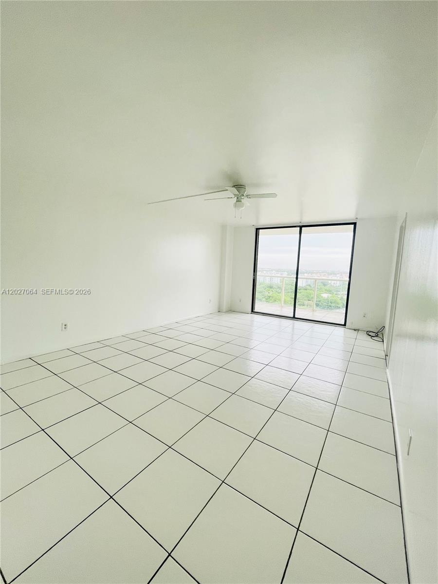 An empty room features white walls, a ceiling fan, and white tiled flooring — 13499 Biscayne Blvd # 1613, North Miami FL 33181, NORTH MIAMI, FL