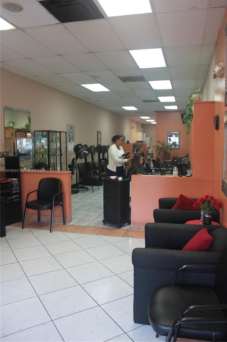 A hair salon interior features black chairs, tiled floors, and a stylist working on a client — 6647 Taft St, Hollywood FL 33024, HOLLYWOOD, FL