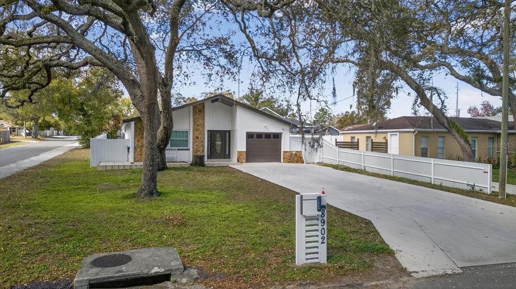 A single-story house with a white facade, stone accents, and a concrete driveway — 8902 N HAMNER AVENUE, TAMPA, FL