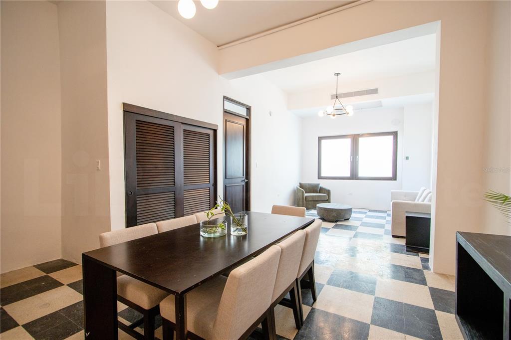 A dining room with a dark table and chairs leads into a living area with checkered flooring — 254-256 SAN FRANCISCO STREET UNIT 204, SAN JUAN, PR