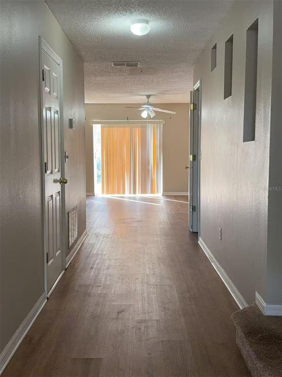 A hallway with wood-look flooring leads to a living area with a sliding glass door — 1206 N FAIRWAY DRIVE UNIT 1206, APOPKA, FL