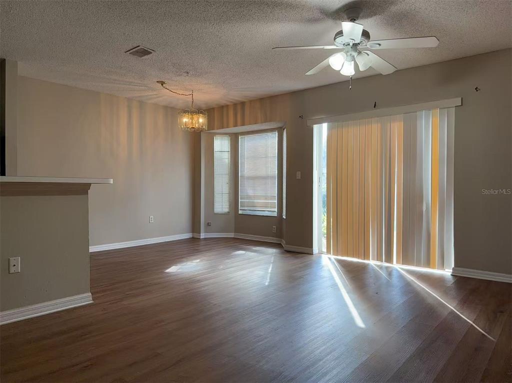 A living room with wood-look flooring, a ceiling fan, and a sliding glass door — 1206 N FAIRWAY DRIVE UNIT 1206, APOPKA, FL