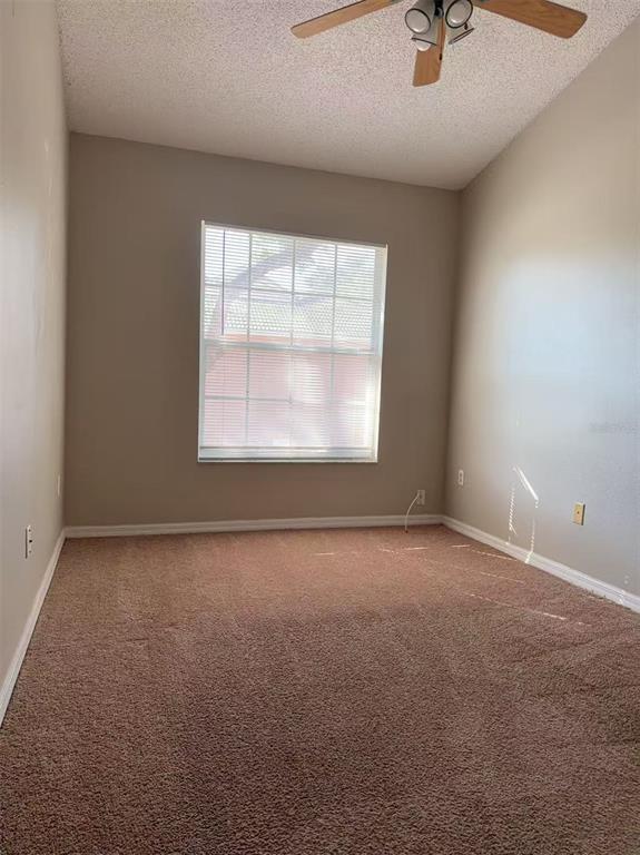 An empty bedroom features beige walls, brown carpet, a ceiling fan, and a single window — 1206 N FAIRWAY DRIVE UNIT 1206, APOPKA, FL