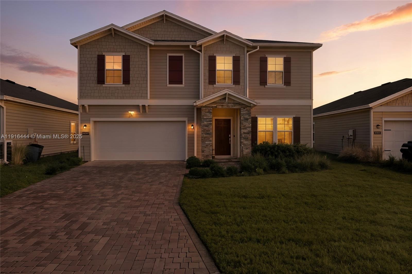 A two-story suburban house features a paved driveway, a two-car garage, and stone accents — 9852 Lemon Balm Way, Jacksonville FL 32219, JACKSONVILLE, FL