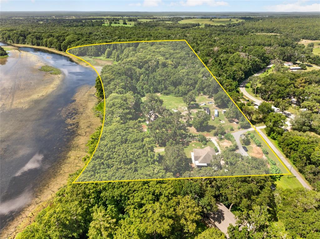 An aerial view shows a house on a wooded lot bordered by a river — 28211 MAGNON DRIVE, BROOKSVILLE, FL