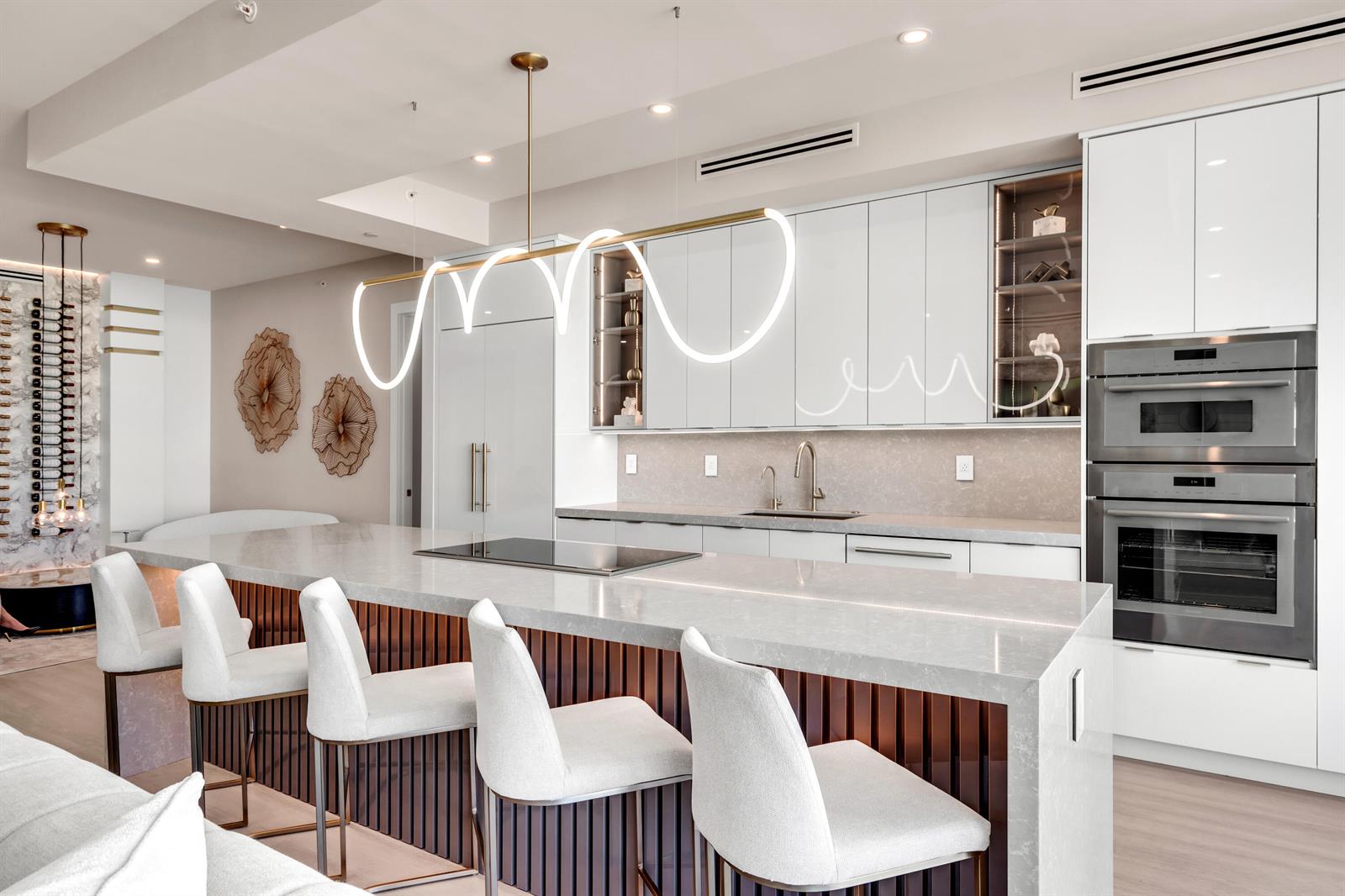 A modern kitchen features a large quartz island with bar seating and white cabinetry — 500 SE Mizner Boulevard # A902, Boca Raton FL 33432, BOCA RATON, FL