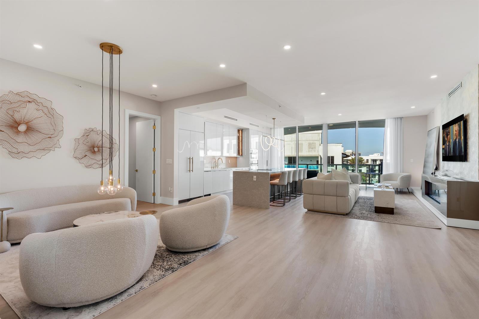 An open-concept living room and kitchen featuring light wood floors, modern furniture, and floor-to-ceiling windows — 500 SE Mizner Boulevard # A902, Boca Raton FL 33432, BOCA RATON, FL