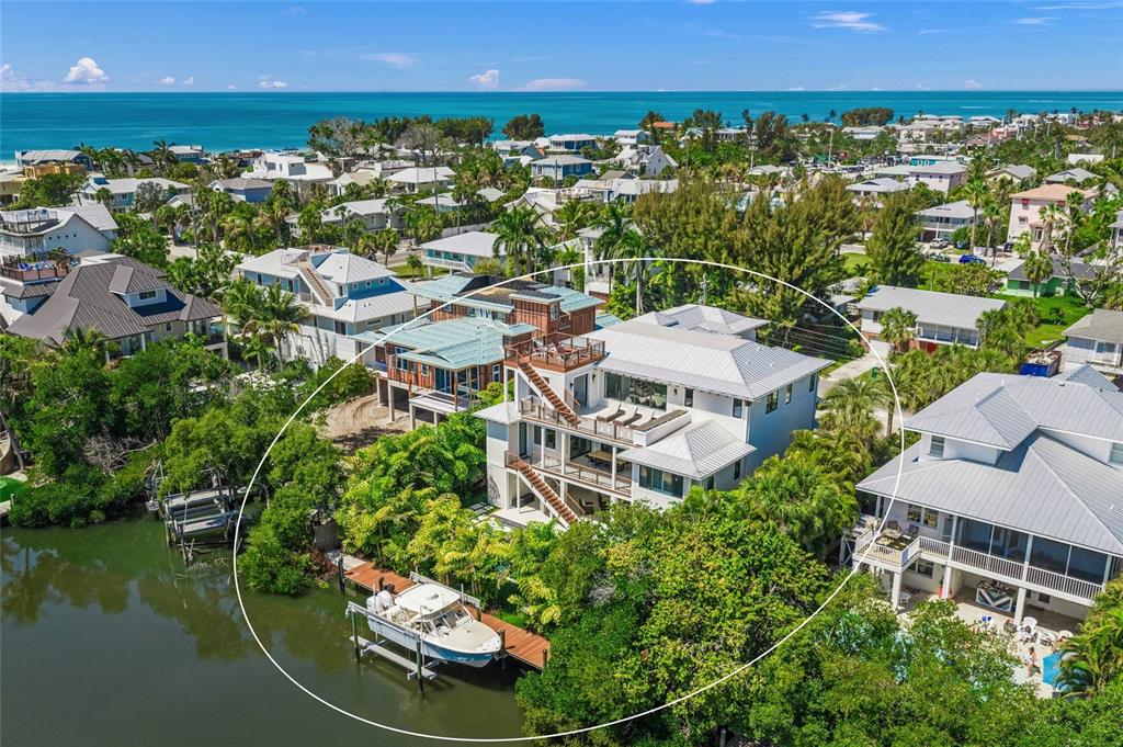 An aerial view shows a multi-story waterfront house with a boat docked at a pier — 209 WILLOW AVENUE, ANNA MARIA, FL