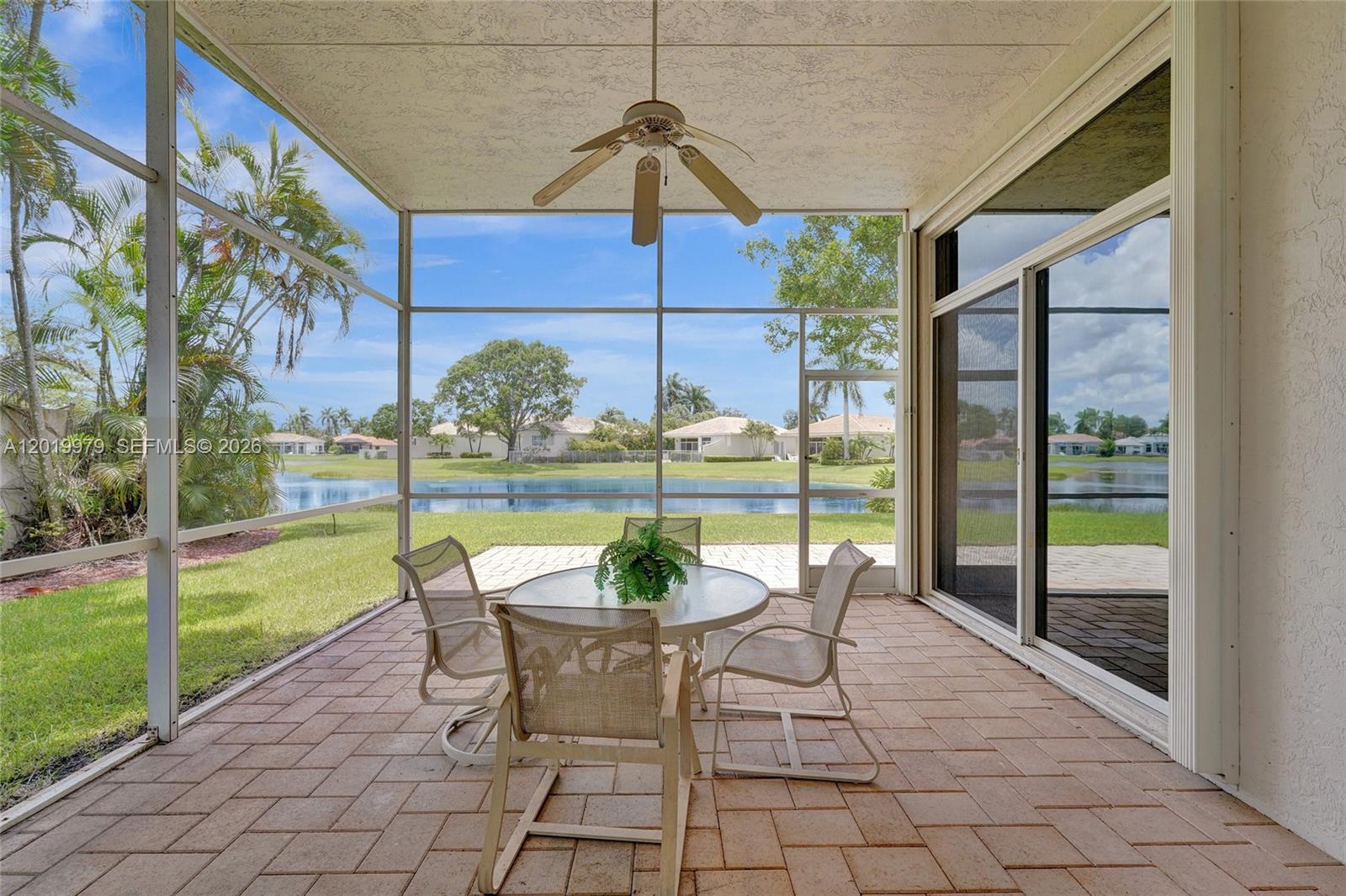A screened-in patio features a dining set, a ceiling fan, and a view of water — 2525 Bay Pointe Ct, Weston FL 33327, WESTON, FL