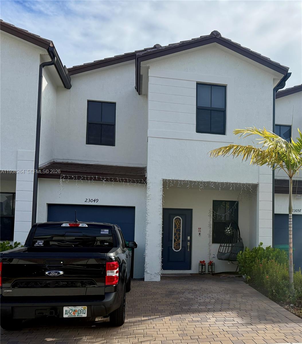 A two-story white townhouse with a dark blue garage door and a paved driveway — 23049 SW 129th Pl, Miami FL 33170, MIAMI, FL