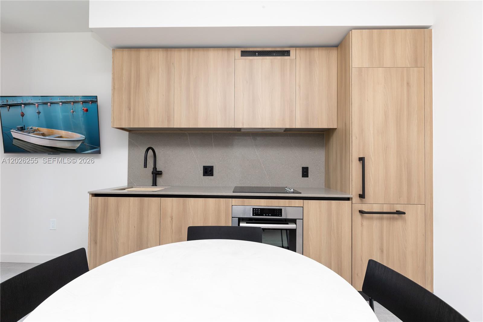 A modern kitchen features light wood cabinetry, a grey stone backsplash, and black hardware — 121 NE 5th St # 510, Miami FL 33132, MIAMI, FL