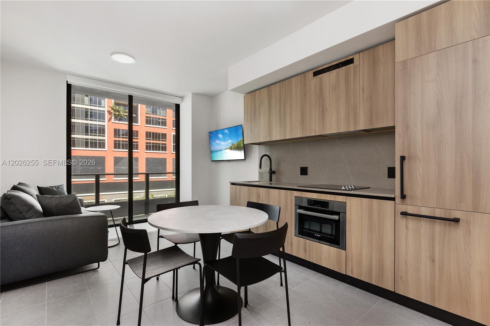 A modern kitchen and dining area features light wood cabinetry, a round table, and balcony — 121 NE 5th St # 510, Miami FL 33132, MIAMI, FL
